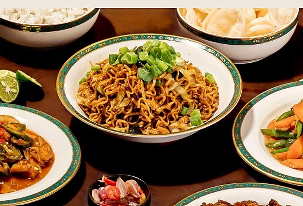Sajian katering DB Production: mi goreng, kerupuk, tumis sayur, dan sambal disajikan di atas meja.